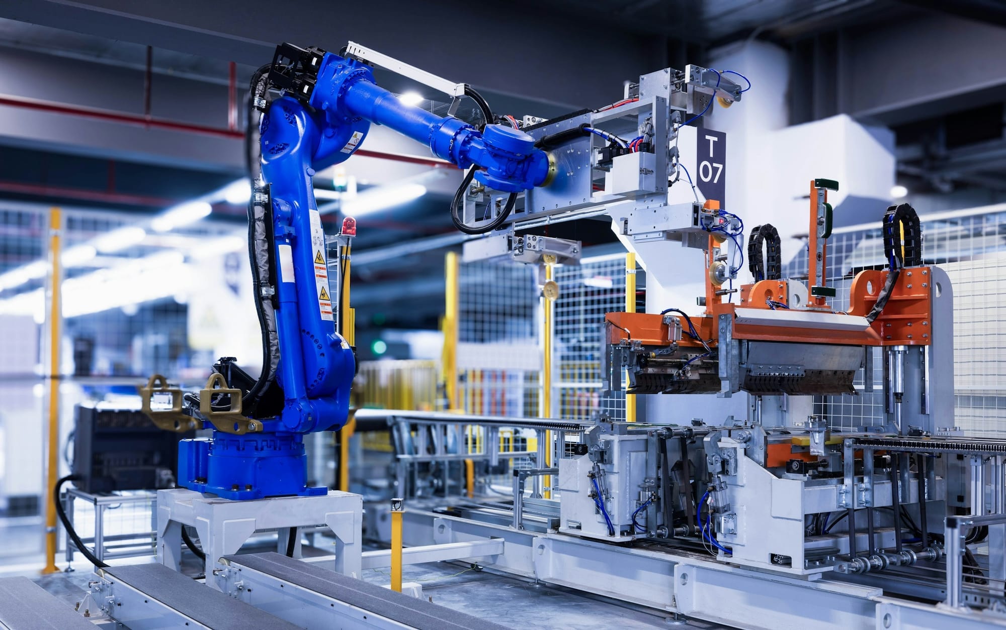 A blue industrial robot arm operating inside a factory.