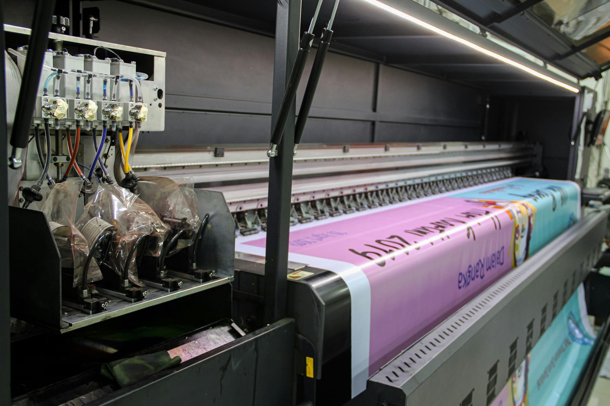 A large-format printing machine producing a colourful printed sheet.