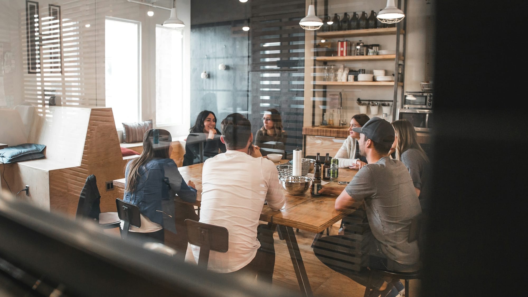 Colleagues gathered around a wooden table in a glass meeting room.