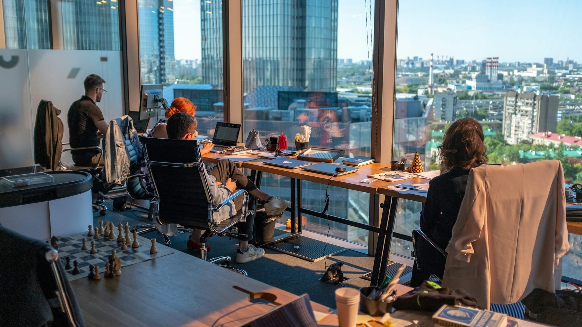 Colleagues working independently in a bright office overlooking a city.