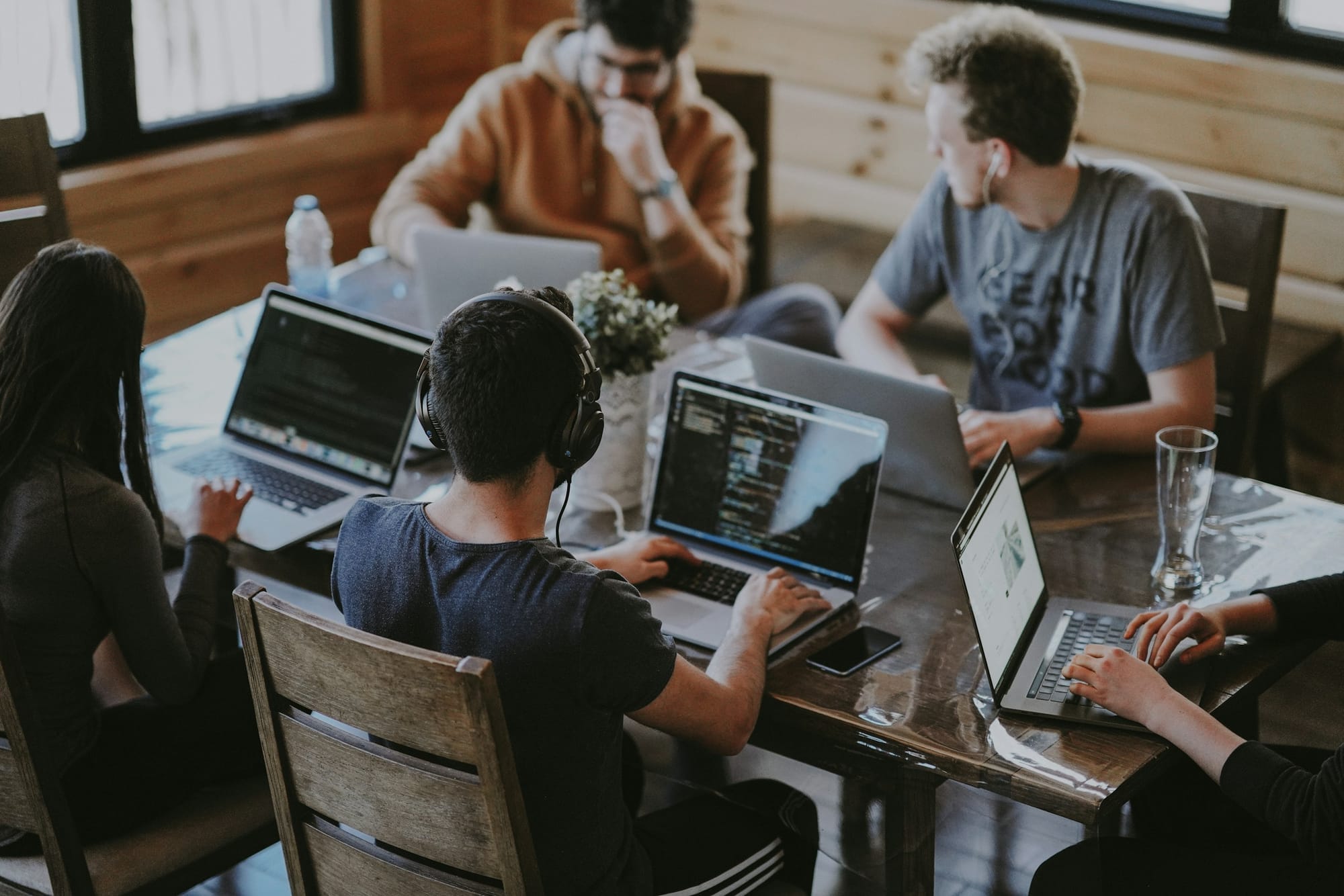 A small team working together around a table with several laptops.