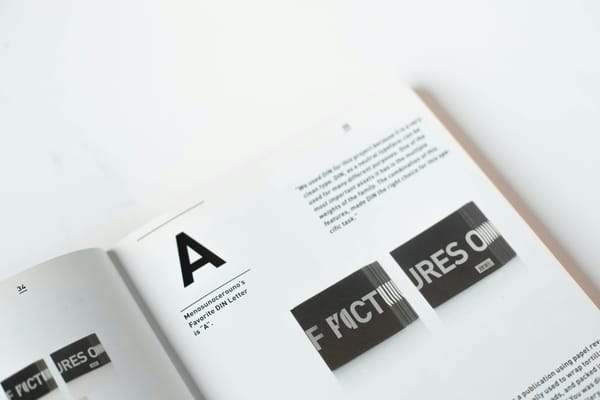 An open editorial design book showing letterforms and printed cards.