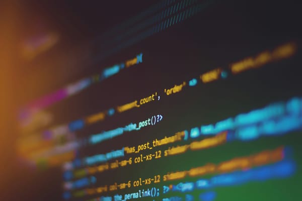 Colourful lines of computer code shown in shallow focus on a dark screen.