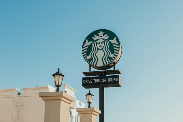 A Starbucks drive-through sign against a clear blue sky.