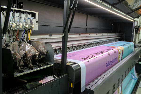 A large-format printing machine producing a colourful printed sheet.