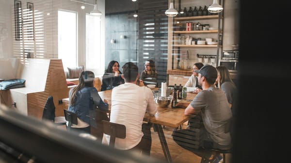 Colleagues gathered around a wooden table in a glass meeting room.