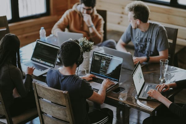 A small team working together around a table with several laptops.